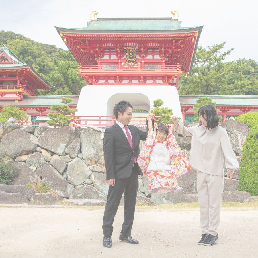 家族写真神社の前で子供を見つめる両親