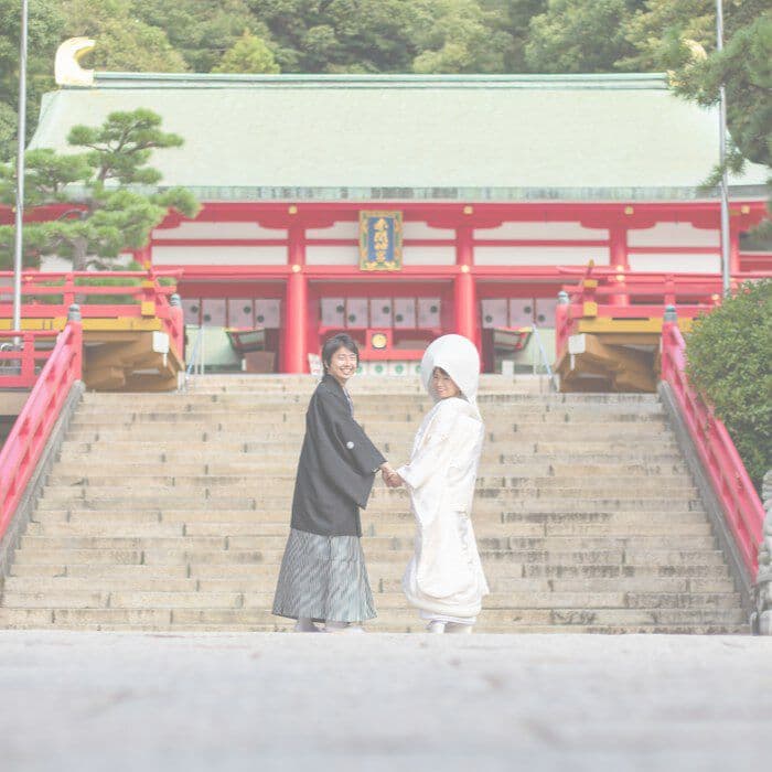 結婚写真神社で振り返る白無垢を着た女性と羽織袴の男性新郎新婦